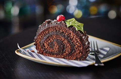 A slice of chocolate yule log with an edible holly leaf on top