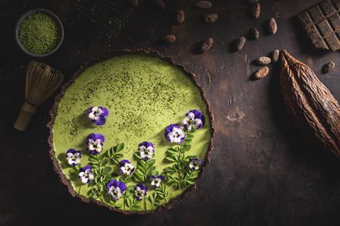 A matcha and chocolate tart with edible purple flowers on top