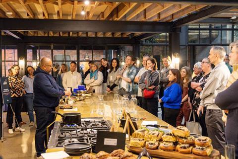 A group of bakers gathers to watch a patisserie demonstration