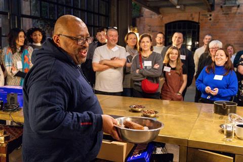 Graham Hornigold covering doughnuts in sugar in front of a happy crowd
