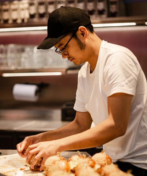 A man in a baseball cap and glasses shaping dough at Gail's Bakery