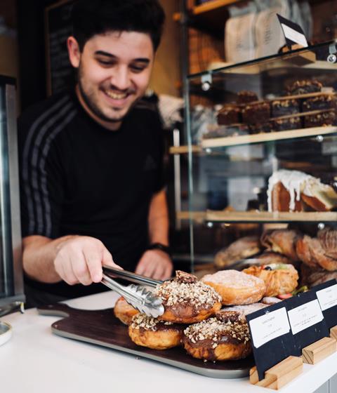 A staff member picks up a Nutella doughnut at a Stir cafe in Cambridge  1542x1800