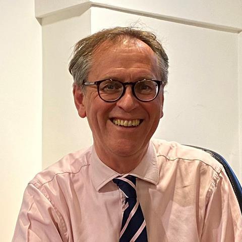 A smiling Alex Waugh in a shirt and tie