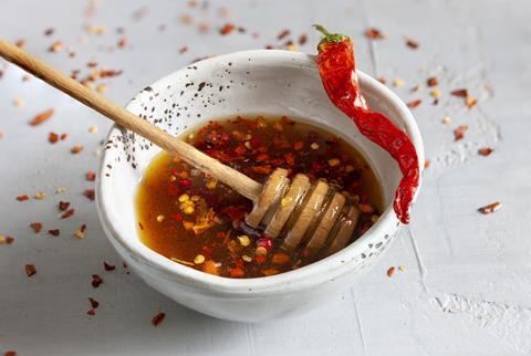 A small bowl of honey with chilli flakes in