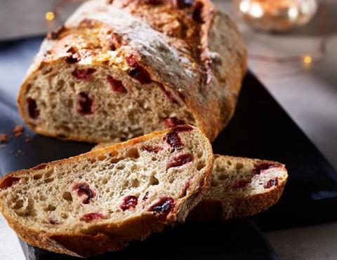 A sourdough loaf with a slice taken out of it, and cranberries inside