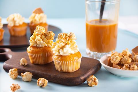 Cupcakes topped with frosting, popcorn and caramel sauce