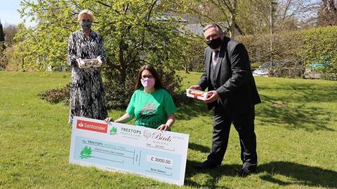 Two women and a man with a giant cheque