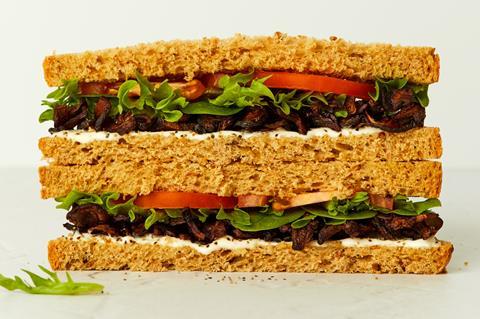 A sandwich with sticky mushrooms, lettuce, and tomato between slices of wholegrain bread