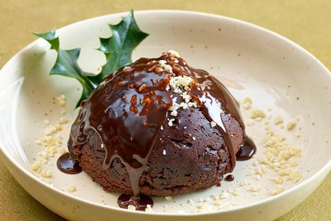 A Christmas pudding with brandy sauce and holly sprig on top