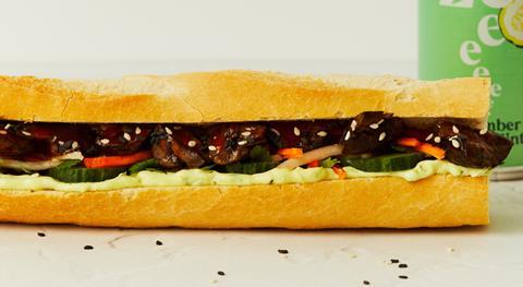 A vegan  Banh Mi with sticky glazed mushrooms, mooli slaw and cucumber in a white baguette