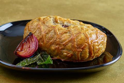 A vegan no beef wellington with roasted red onion on a black plate