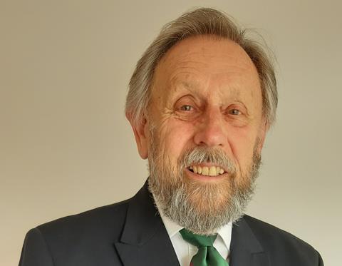 Patrick Wilkins, an older man with beard in a black suit and green tie