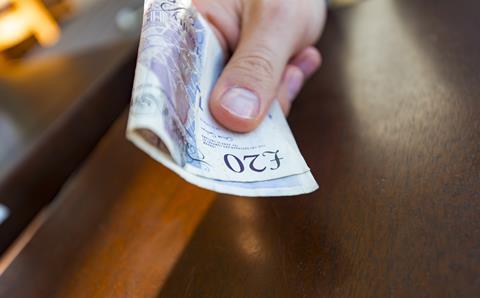 A person handing over a £20 note