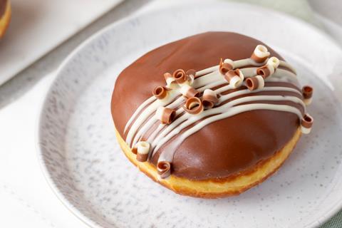 A chocolate covered doughnut with chocolate curls on top