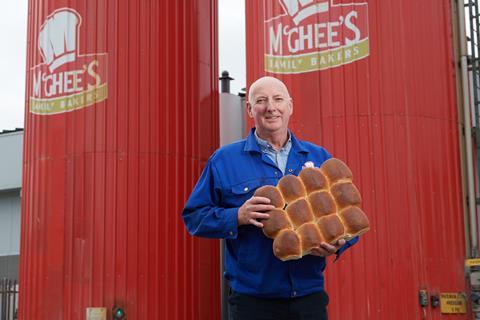 A man in a blue jacket outside the silos that say McGhee's Family Bakers