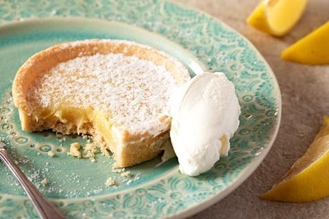 Lemon tart on a turquoise plate with a dollop of cream