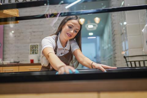 A woman wiping down surfaces in a bakery