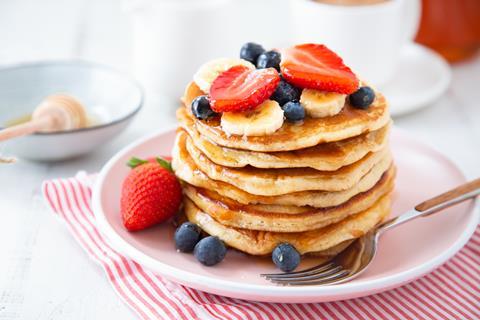 A stack of American pancakes with banana, blueberries, and strawberries on top