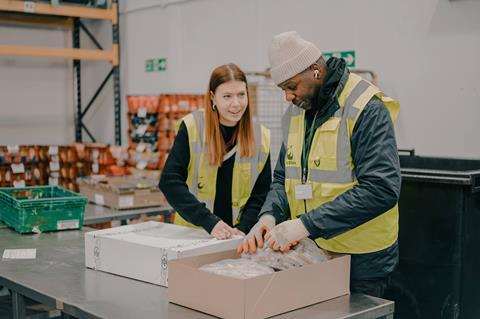 Two people in a FareShare warehouse sorting boxes of food
