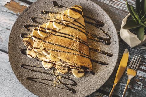 A folded crepe with banana and chocolate sauce on top