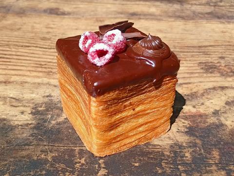 A cube croissant with chocolate ganache and sugar dusted raspberries on top