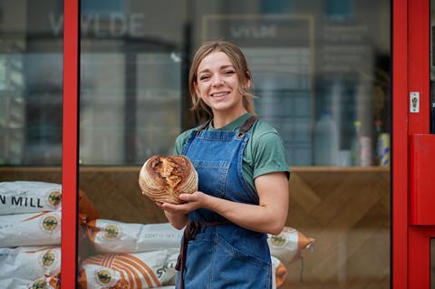 Naomi Spaven standing outside Wylde Bakery holding a sourdough loaf