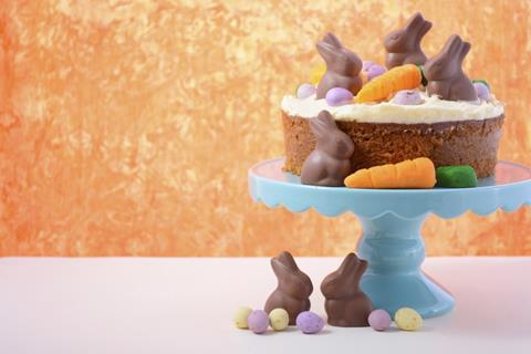 A carrot cake with chocolate bunnies and carrots on top