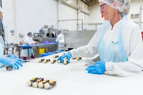 Lazy Day Foods - A worker picks up mini caterpillar cakes from a production line at the Harthill bakery site - 2100x1400