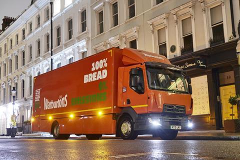An orange Warburtons lorry driving through London