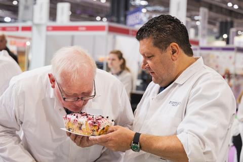 Two men judging a cake, with one man sniffing it closely
