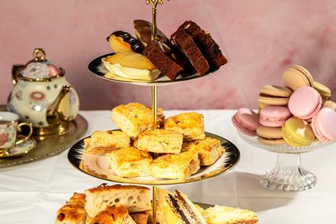 An afternoon tea stand with focaccia, savoury scones, and cakes