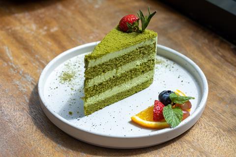 A slice of matcha layer cake on a speckled plate