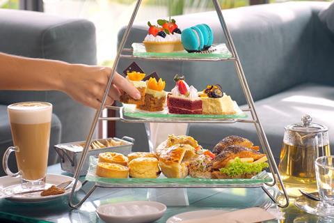 An afternoon tea stand loaded with macarons, cakes and sandwiches