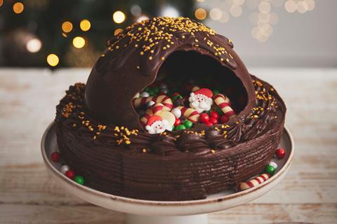 A chocolate cake with a smashed chocolate dome on top, revealing Christmas themed sweets