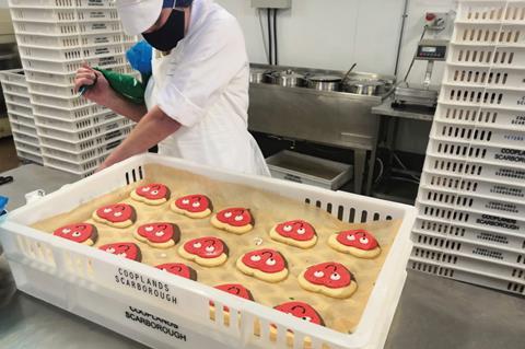 A baker hand piping icing onto Valentine’s Day biscuits