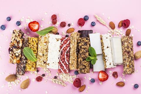 A row of different granola bars with fruit on a pink background