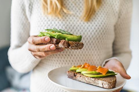Woman in white jumper eating avocado on toast