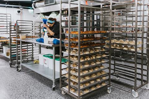 A baker at work piping frosting onto buns at The Danish Bakery