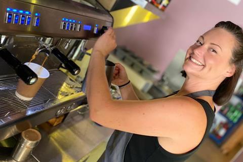 A smiling woman making coffee in a bakery in Scotland