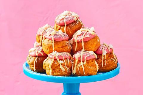 Profiteroles with pink fondant and white chocolate on a blue cake stand