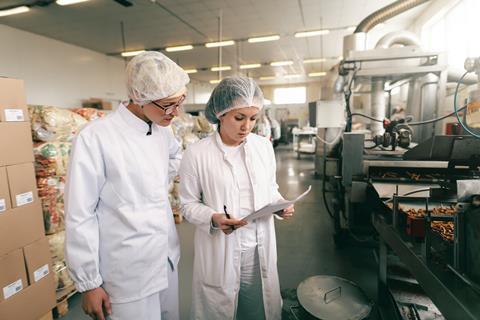 Two ladies look at a piece of paper in a bakery production site