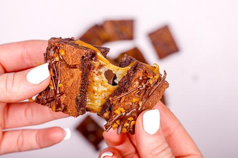 A caramel filled gluten-free brownie being pulled apart by a white woman's hands