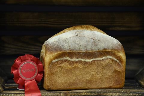 A soft and pillowy white loaf with flour on top next to a winner's rosette