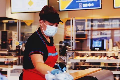 A Greggs employee wearing a mask while cleaning a site