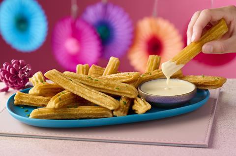Churros with a cheesy dipping sauce on a pink background