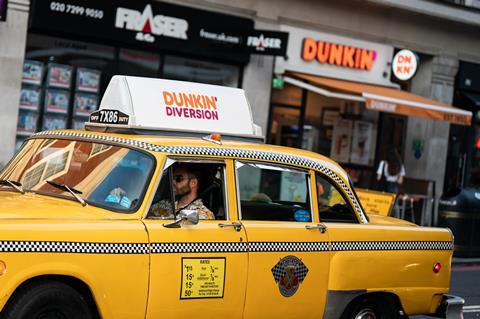 An American yellow can driving round in London by Dunkin'