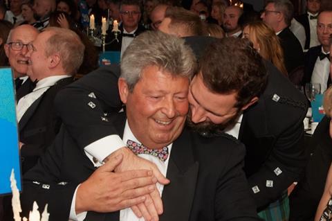 Two men hugging in delight at an award win