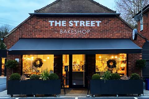 A brick bakery called The Street Bakeshop with bright lights inside