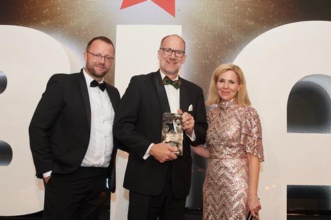 A smiling Peter Doughty-Cook (centre), owner of Peter Cooks Bread, celebrates after being given the Baker of the Year 2022 trophy by Brook Food & Bakery Equipment's Mike Moran (left) and celebrity host Sally Phillips