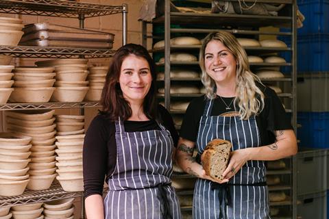 Two women in aprons stood in a bakery